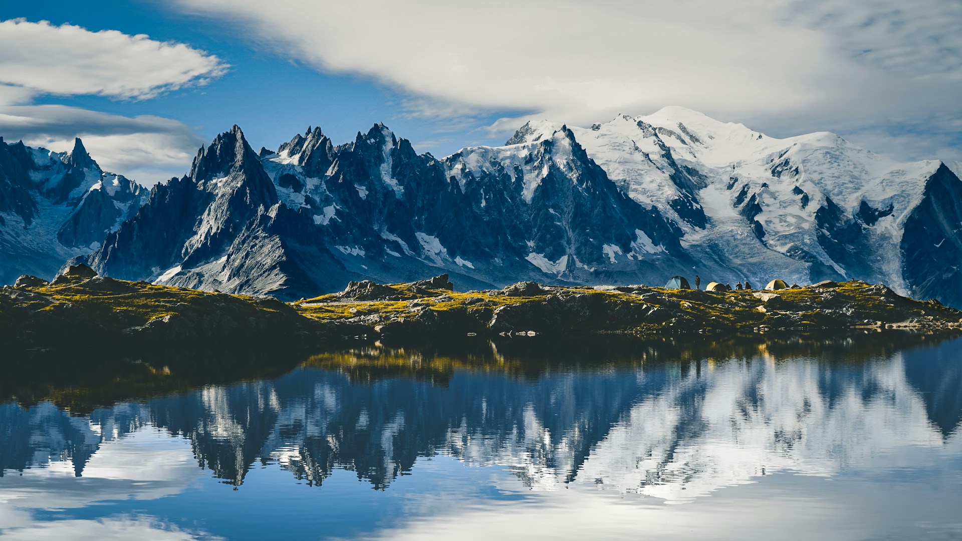Mountain range with grass and water in front