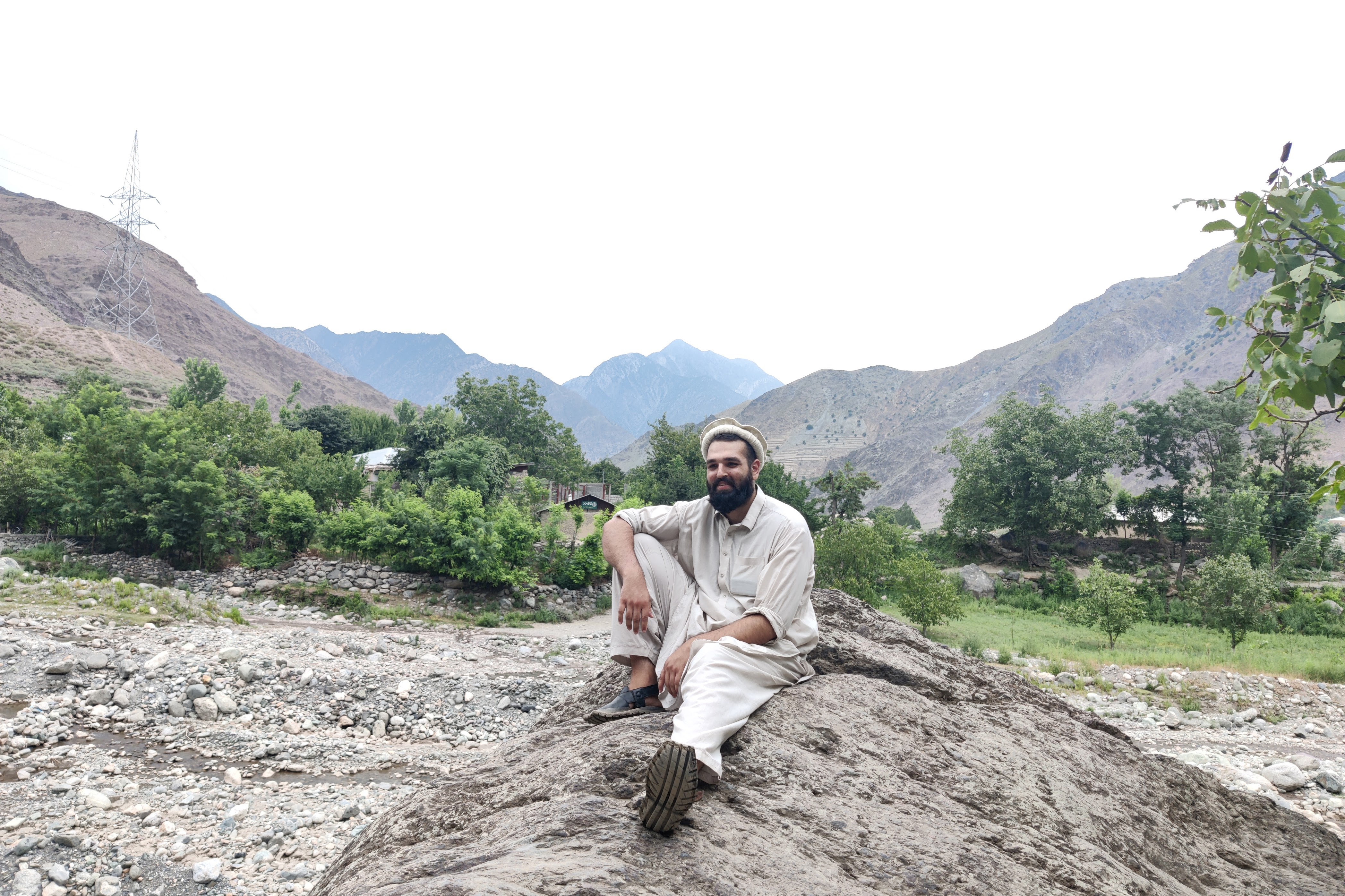 man sitting on rock with mountains behind