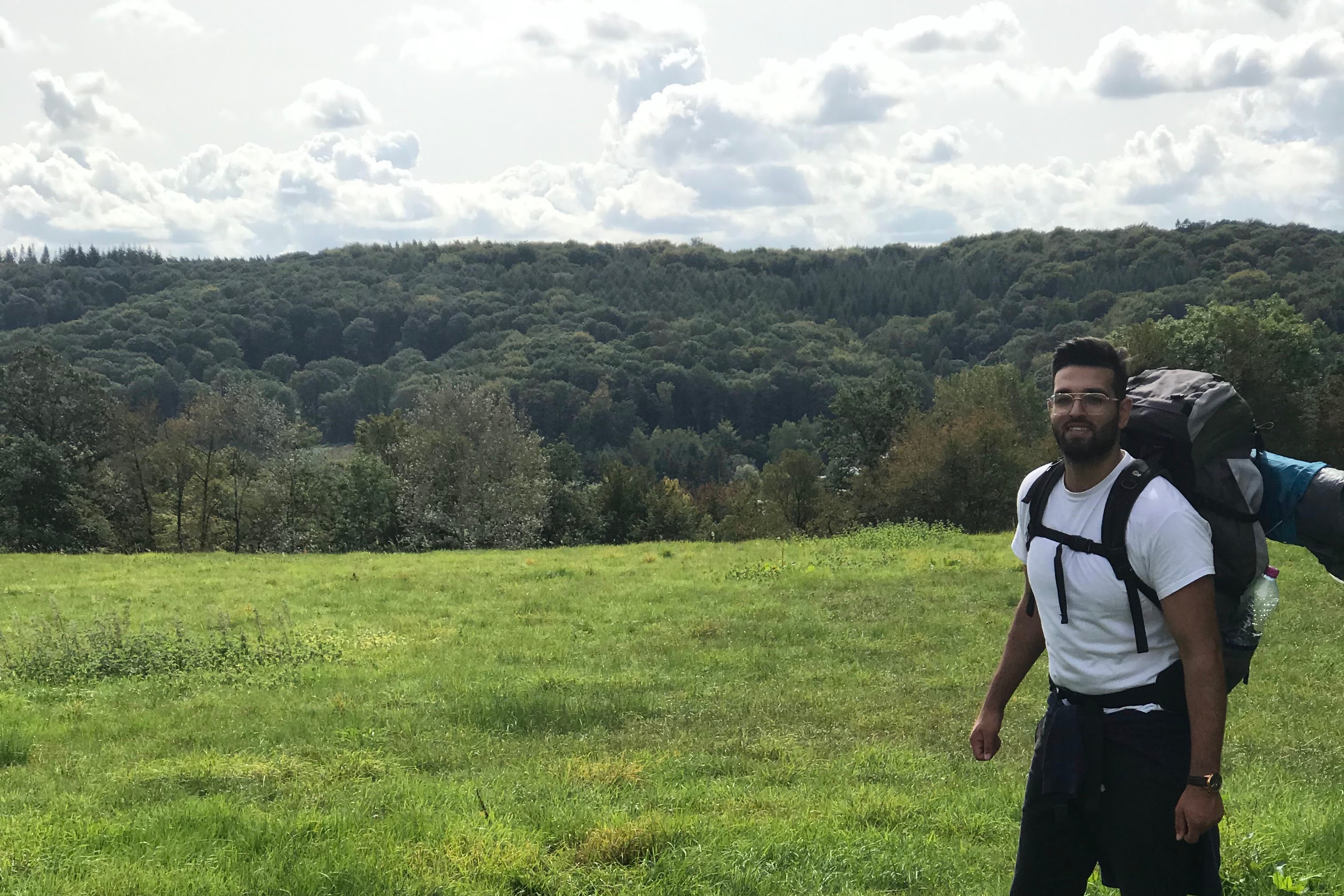 man with backpack with forest behind